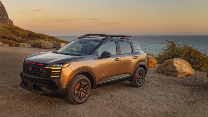 Современный SUV припаркован у скалистого побережья во время заката, океан в фоне.